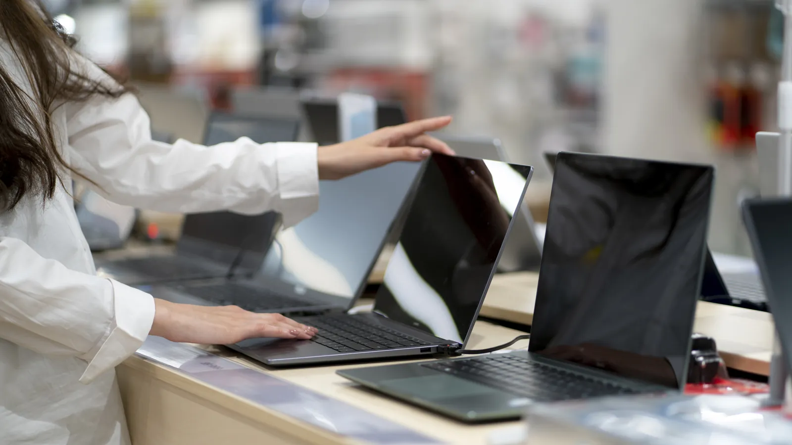 Cliente ajusta con la mano la pantalla de un notebook en una tienda, ejemplo de cómo tocar un producto aumenta las ganas de comprarlo