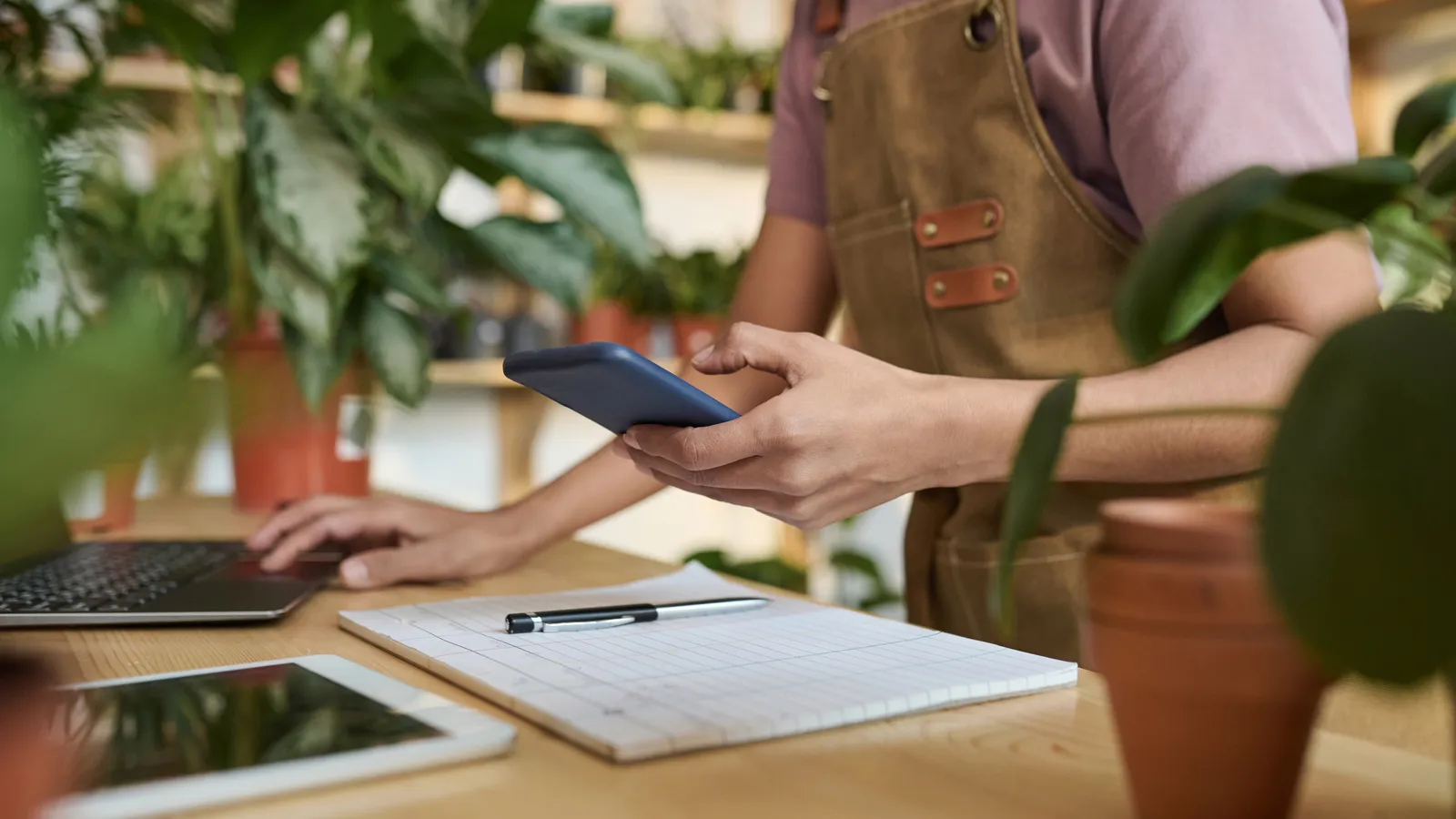 Dueño de una tienda de plantas enviando mensajes a sus clientes desde el celular